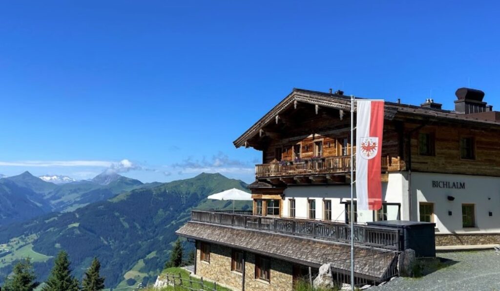 Traditionelle Almhütte Bichlalm im Zillertal mit Tiroler Flagge und Blick auf die umliegenden Berge