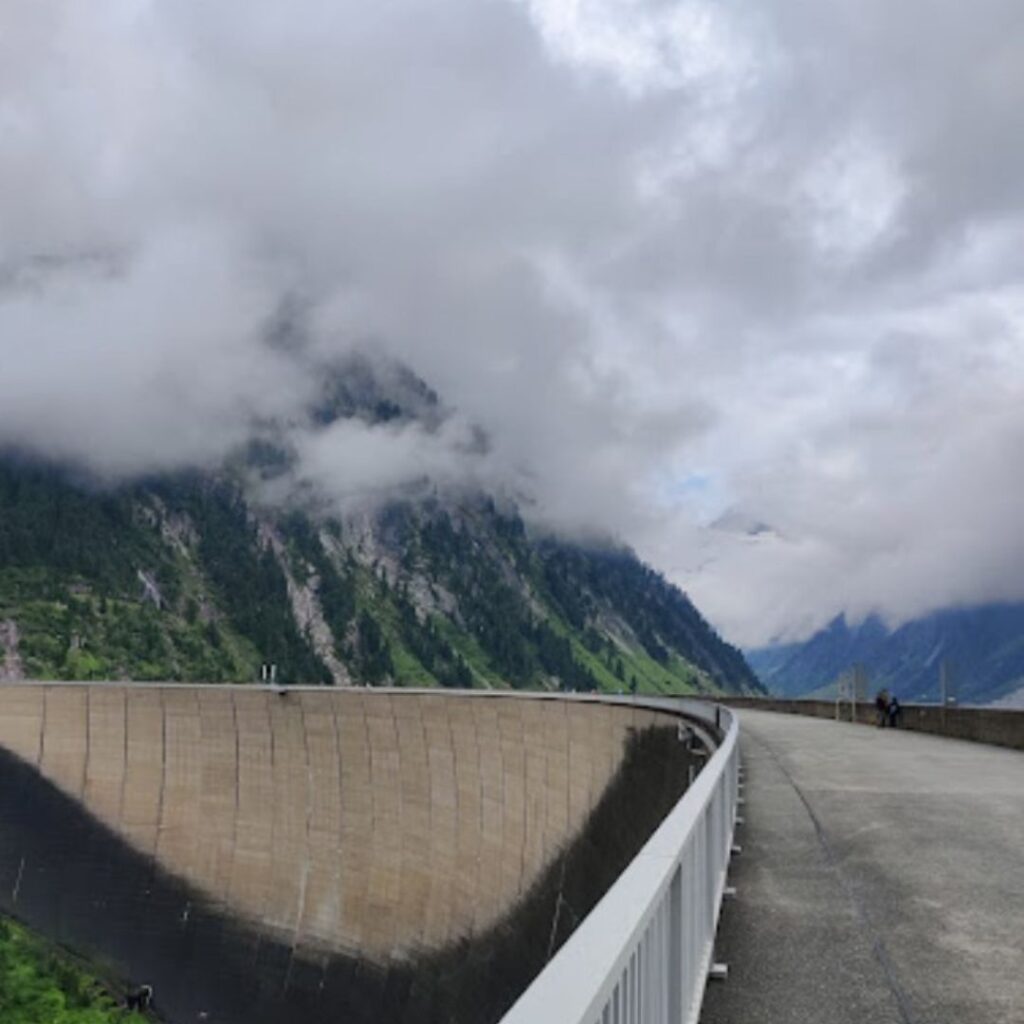 Blick auf die Staumauer des Schlegeis Stausees mit wolkenverhangenen Bergen im Hintergrund.